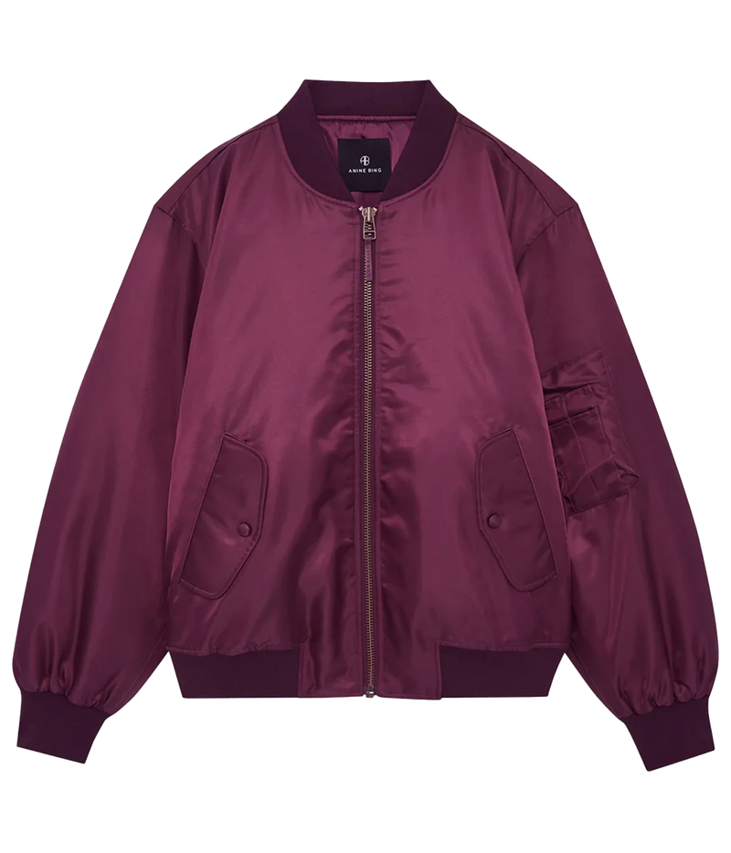 A satin bomber jacket in a deep plum purple color, featuring a front zipper, ribbed collar, cuffs, and hem, with flap pockets on the front and a utility pocket on the sleeve, shown against a plain white background.