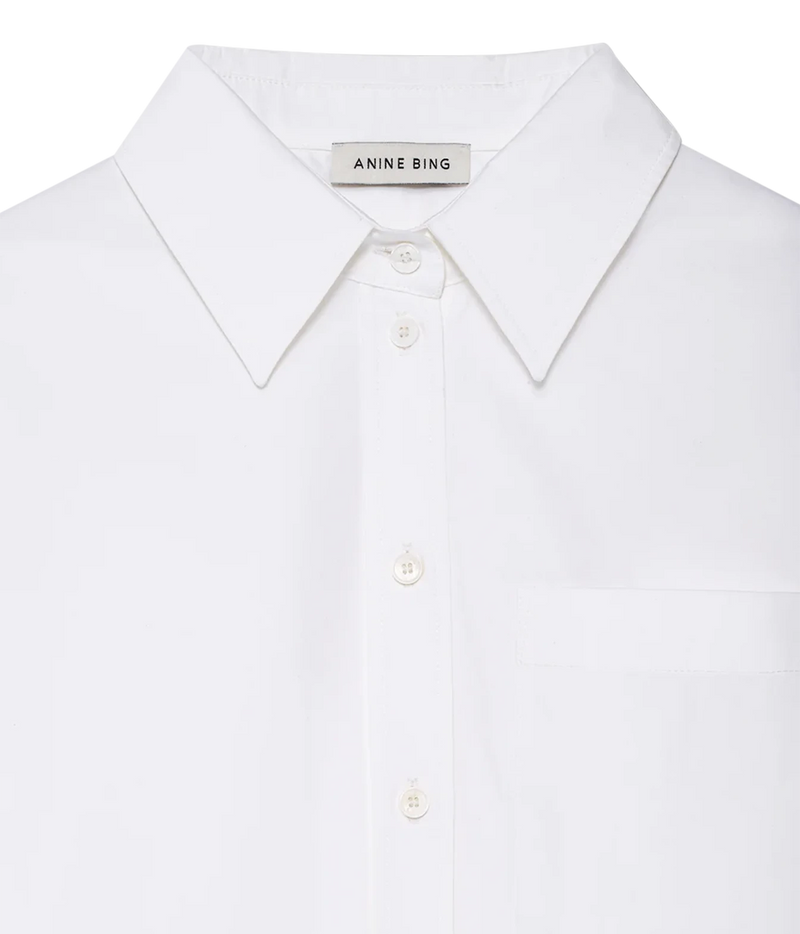 Close-up of a white Anine Bing button-down shirt with a classic pointed collar and matching buttons, set against a clean white background.
