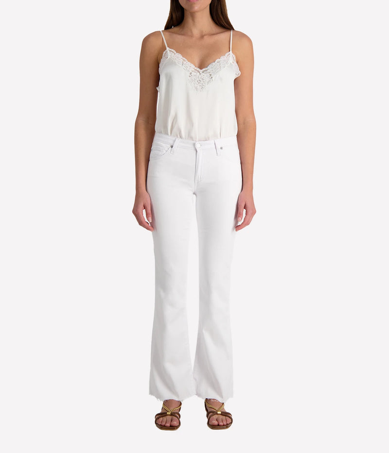 Person wearing white jeans and a white lacy camisole on a white background.