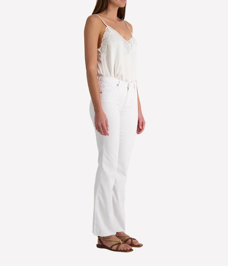 Person wearing white jeans and a white lacy camisole on a white background.