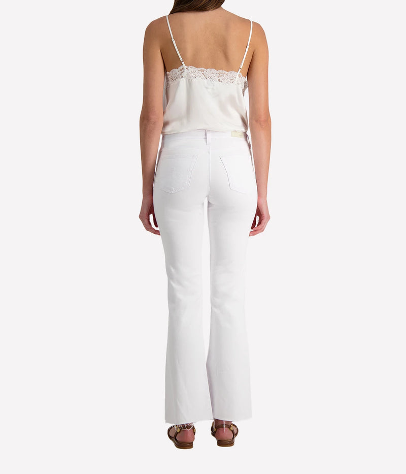 Person wearing white jeans and a white lacy camisole on a white background.