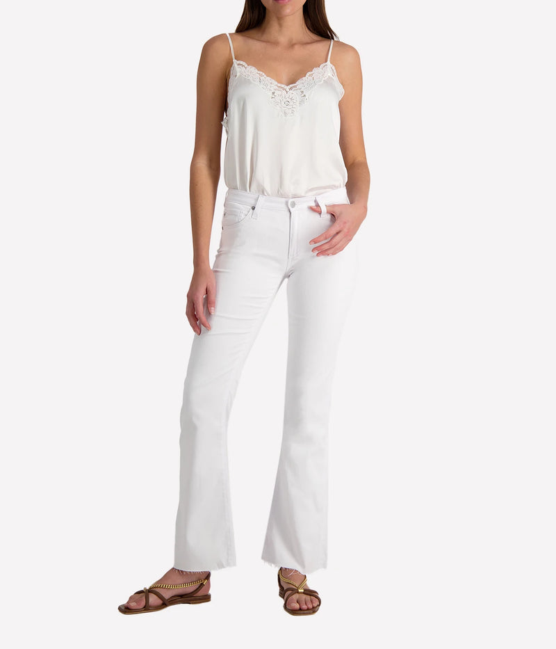 Person wearing white jeans with a silk lacy camisole on a white background.
