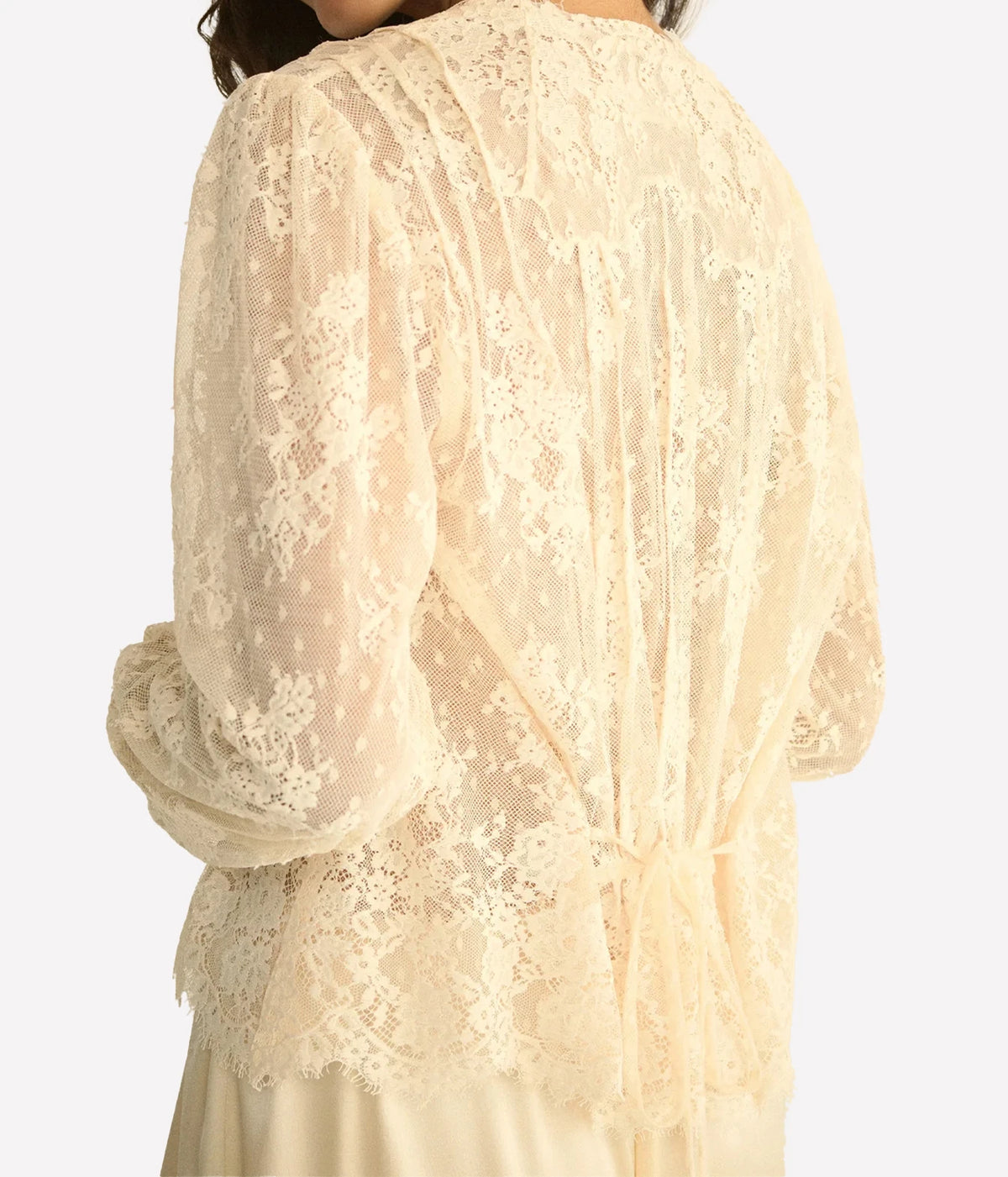 Back view of a model wearing the DÔEN Amaline Top In Candlelight, showing the all-over lace, gathered cuffs and scalloped hem