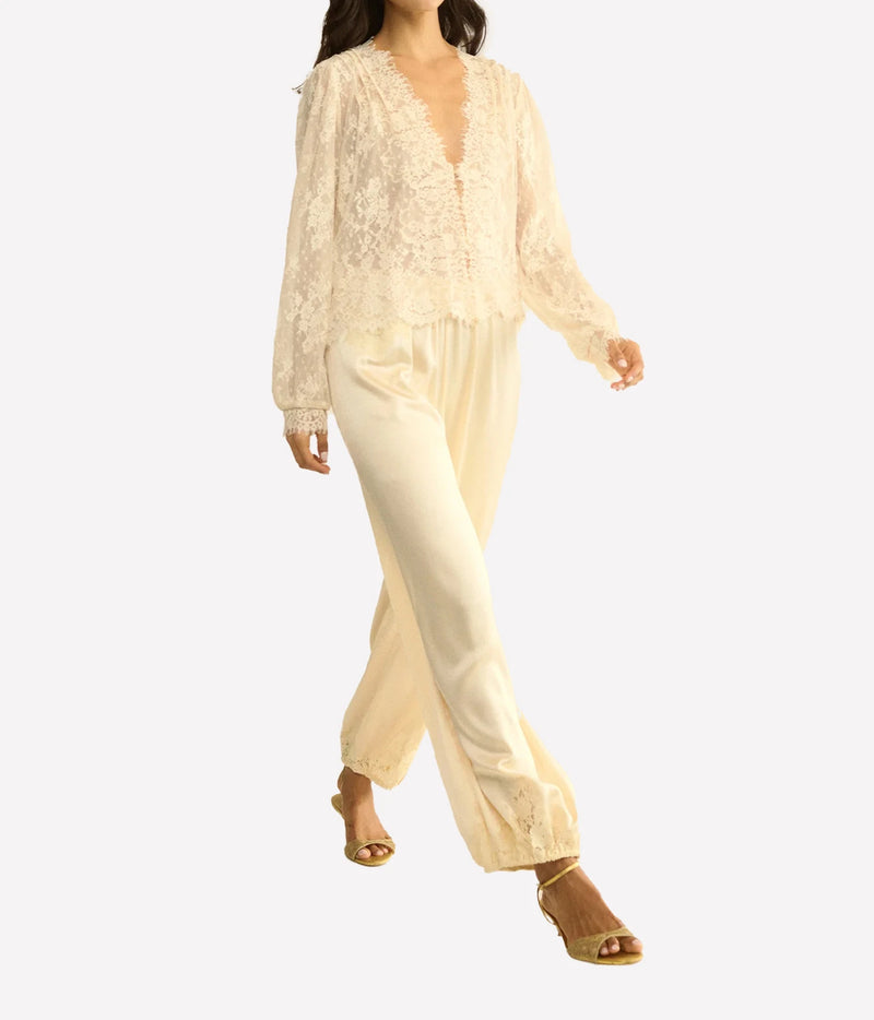 Model walking in the DÔEN Amaline Top In Candlelight with cream satin trousers and tan strappy sandals
