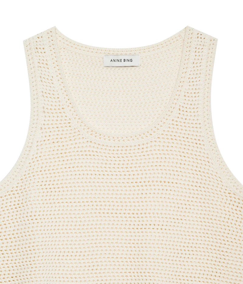 Close-up of a cream-colored open-knit tank top by Anine Bing, showing the fine mesh texture and the brand label at the neckline.