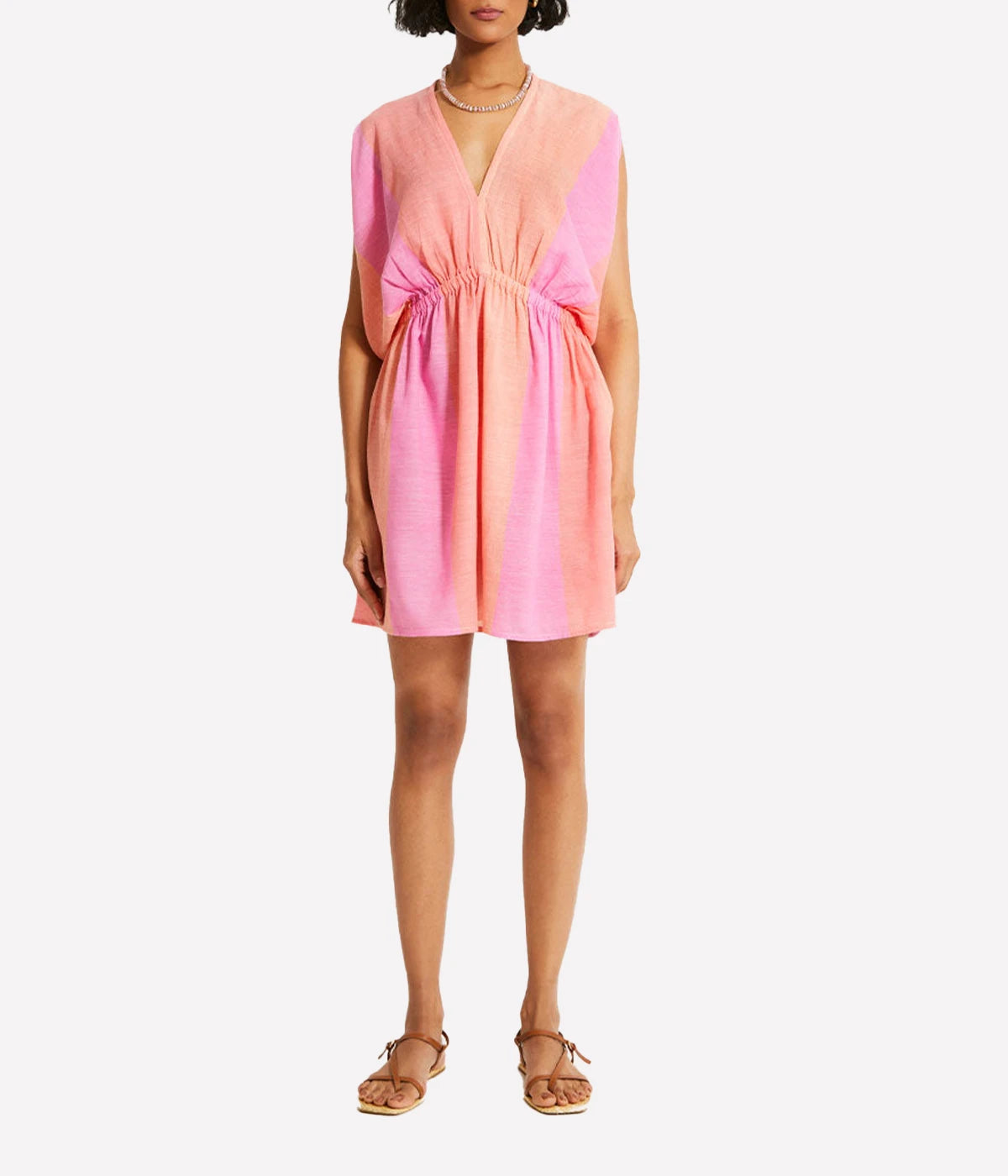 A gauzy short dress with dolman sleeves and an ombre colour block in pink, blush, and peach, styled with sandals for a relaxed resort-ready look.