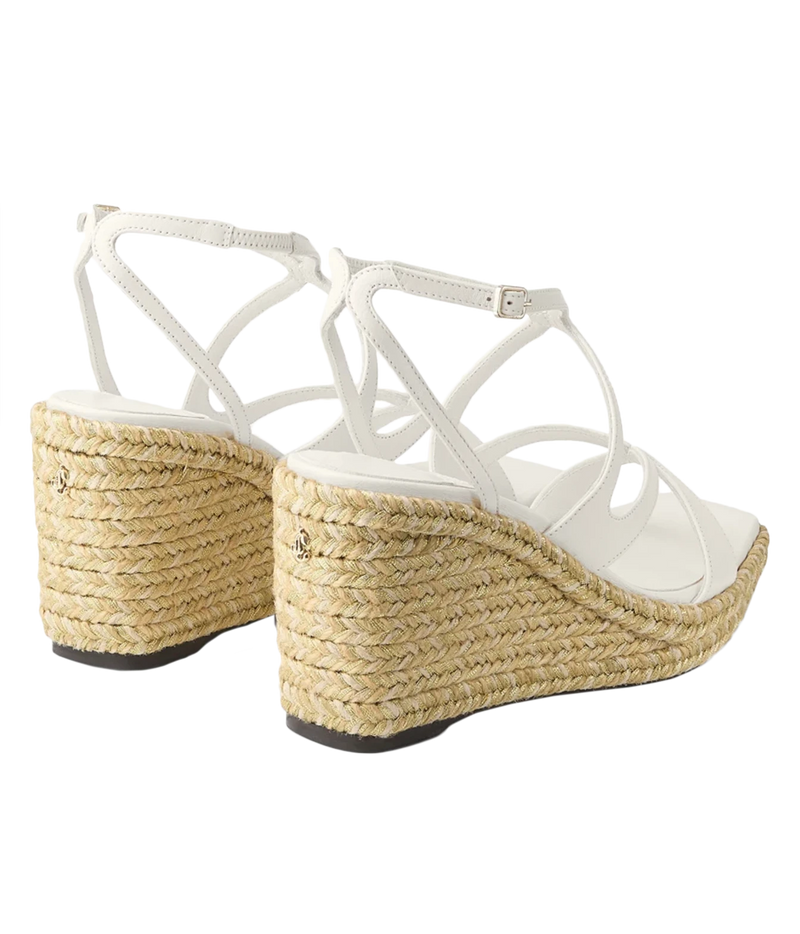 White strappy wedge sandals with woven jute espadrille-style heels, shown from a side-rear angle on a white background.