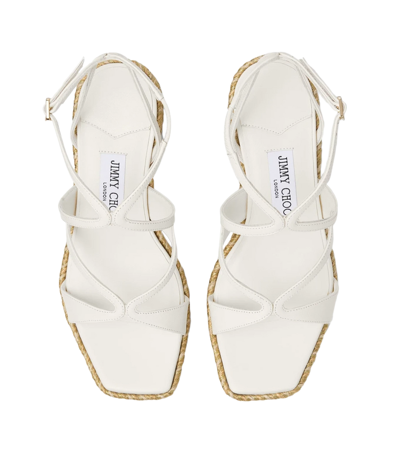 A pair of white leather strappy sandals with espadrille-style woven jute soles, shown from a top-down view on a white background. The Jimmy Choo brand name is visible on the insoles.