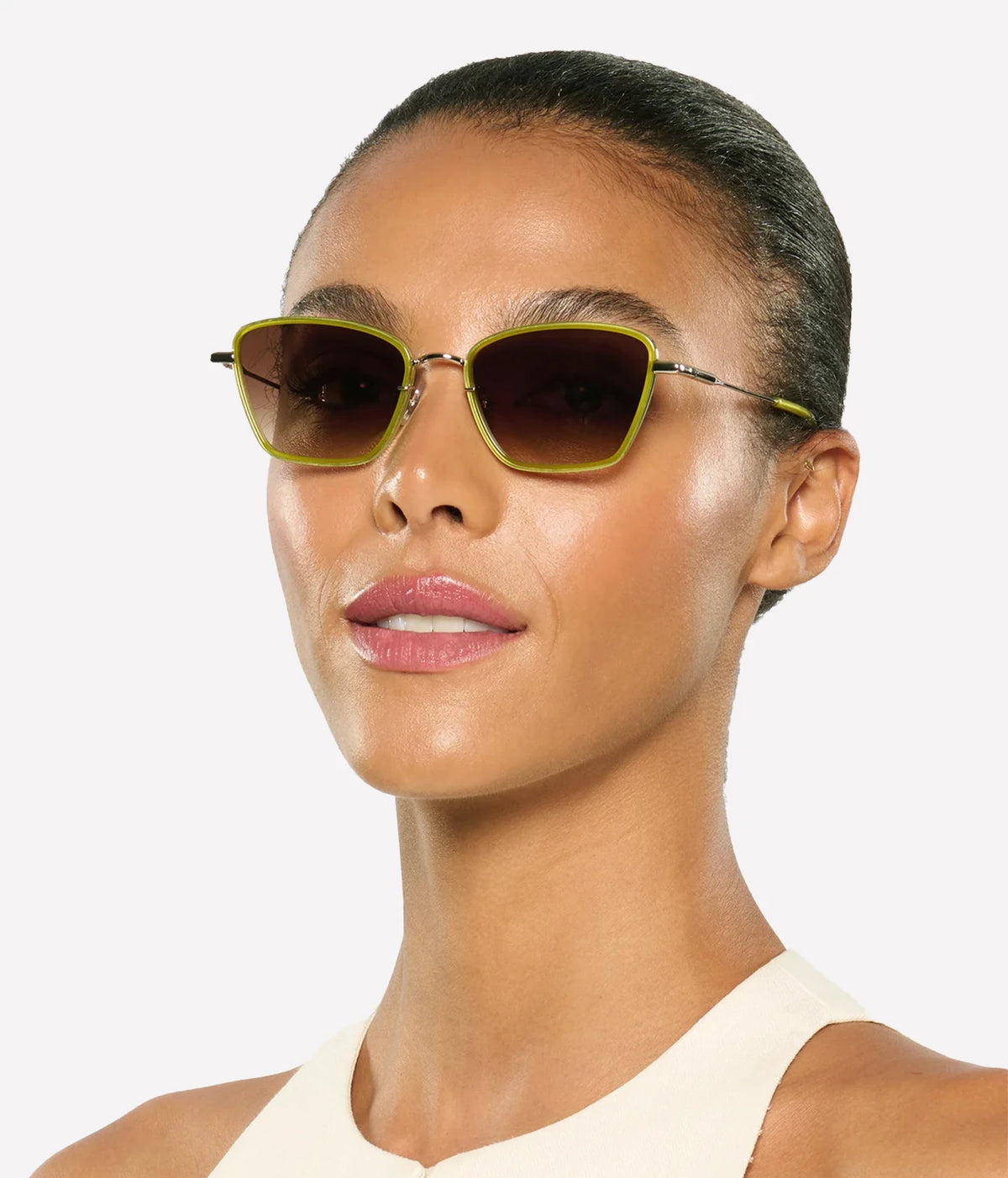Three-quarter view of a model with her hair pulled back wearing the KREWE Bella Sunglasses in Silver Chartreuse with a cream top