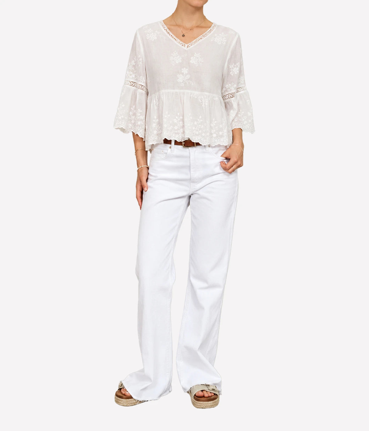 Woman wearing the M.A.B.E Sisi embroidered top in Ivory with white jeans, full-length front view.
