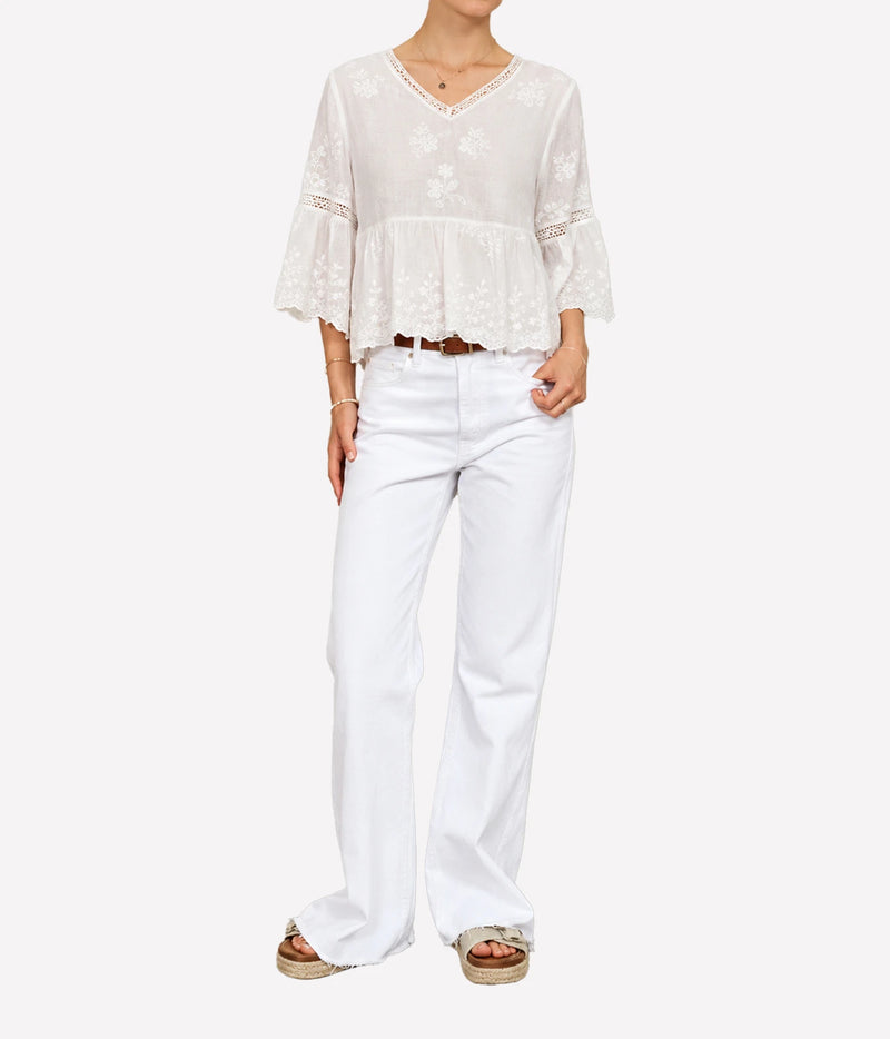 Woman wearing the M.A.B.E Sisi embroidered top in Ivory with white jeans, full-length front view.