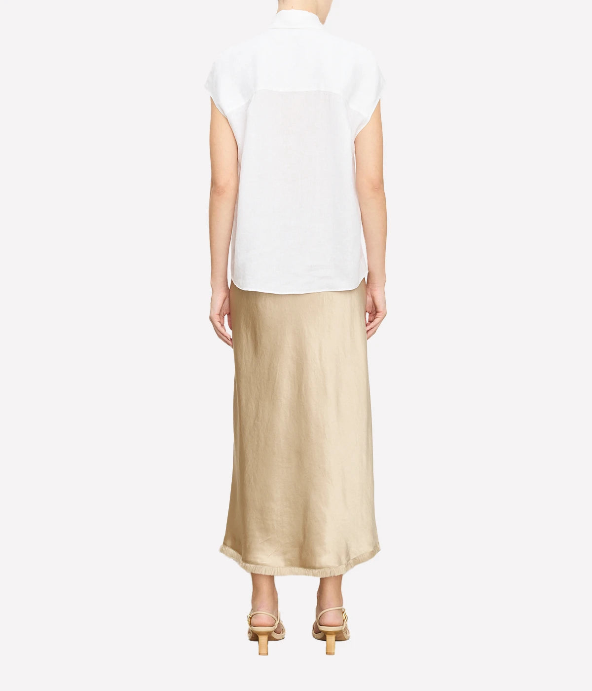 Relaxed linen blouse with cap sleeves, styled with tailored trousers for a polished look.