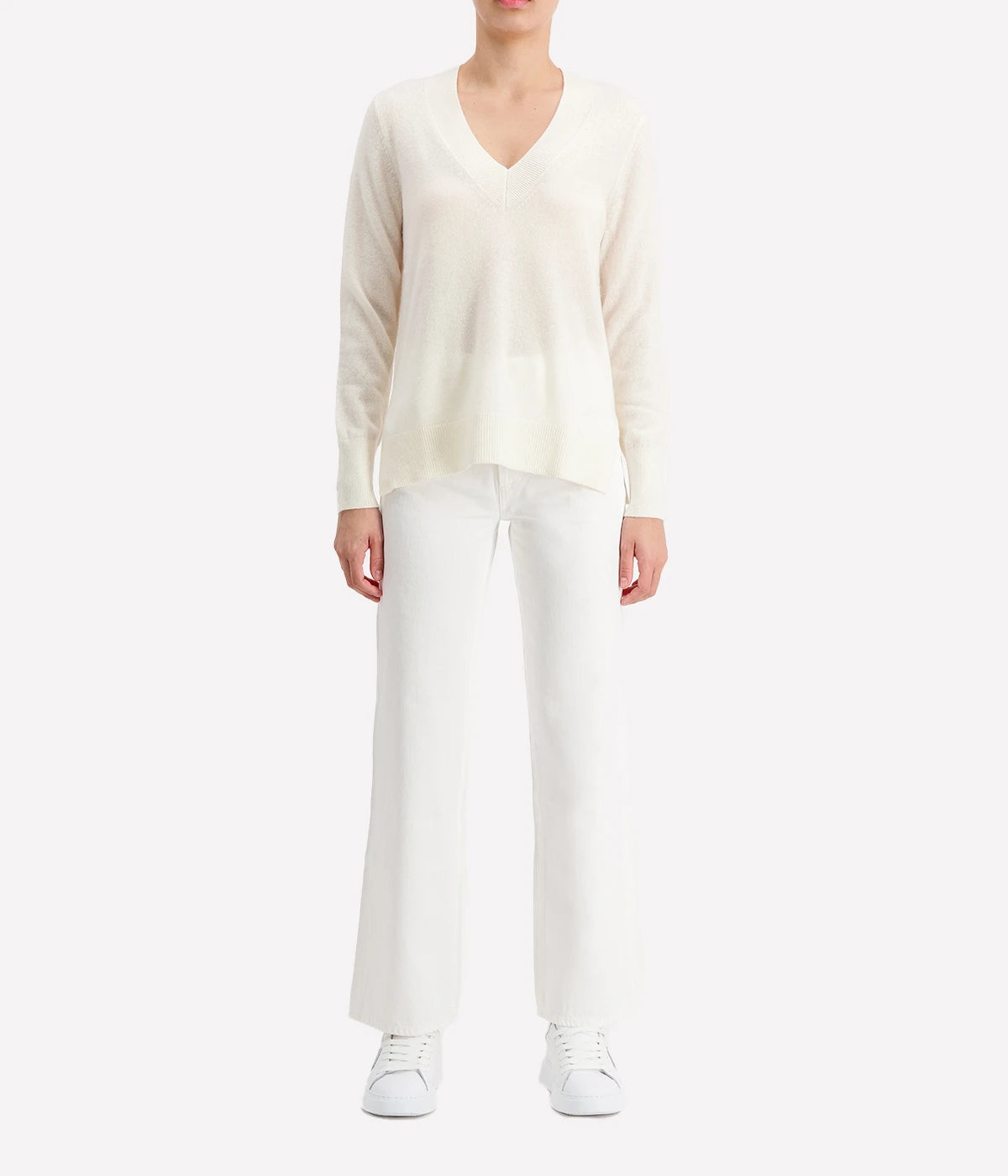 Luxurious cashmere V-neck sweater in leaf heather, styled with jeans and boots for a cosy yet refined look.