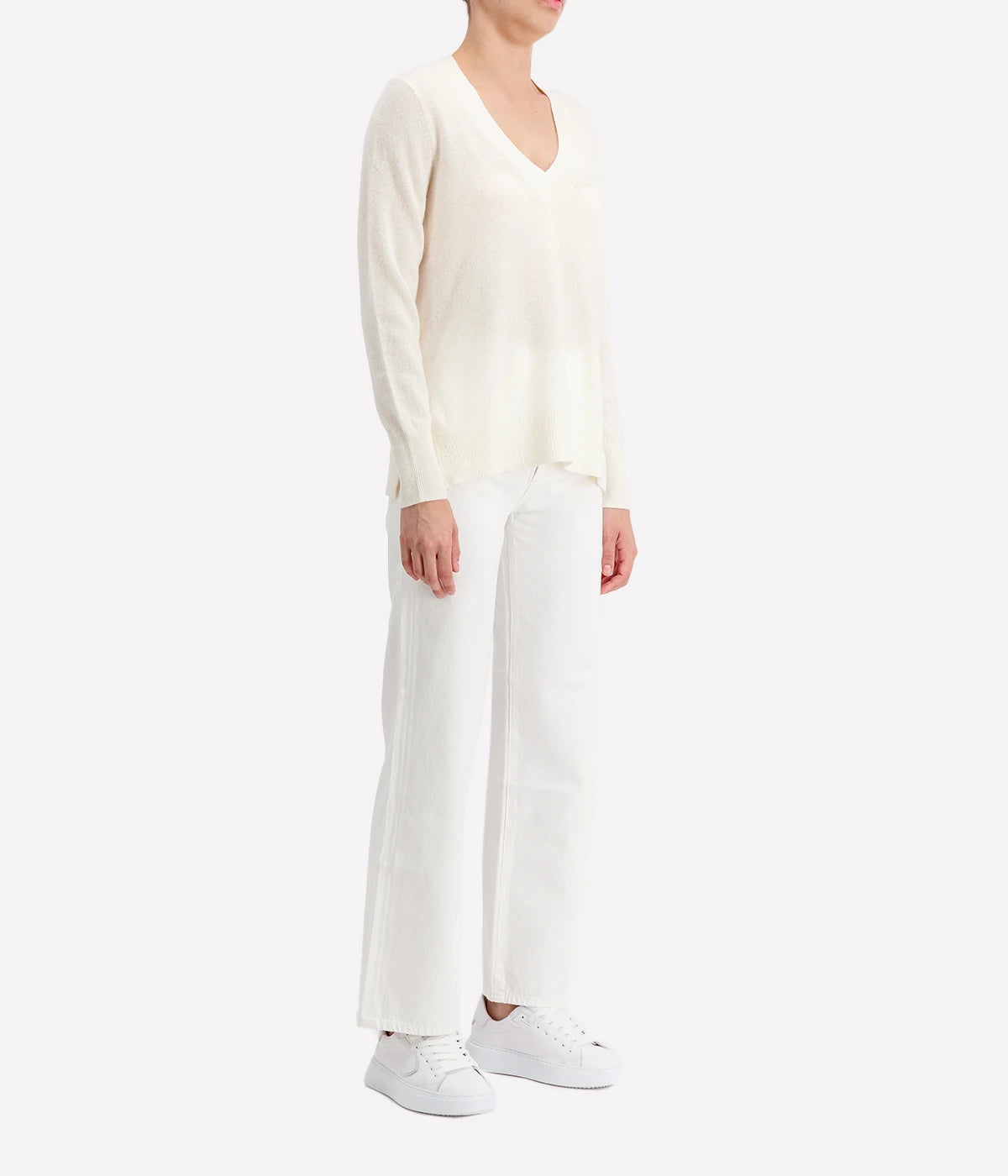 Luxurious cashmere V-neck sweater in leaf heather, styled with jeans and boots for a cosy yet refined look.