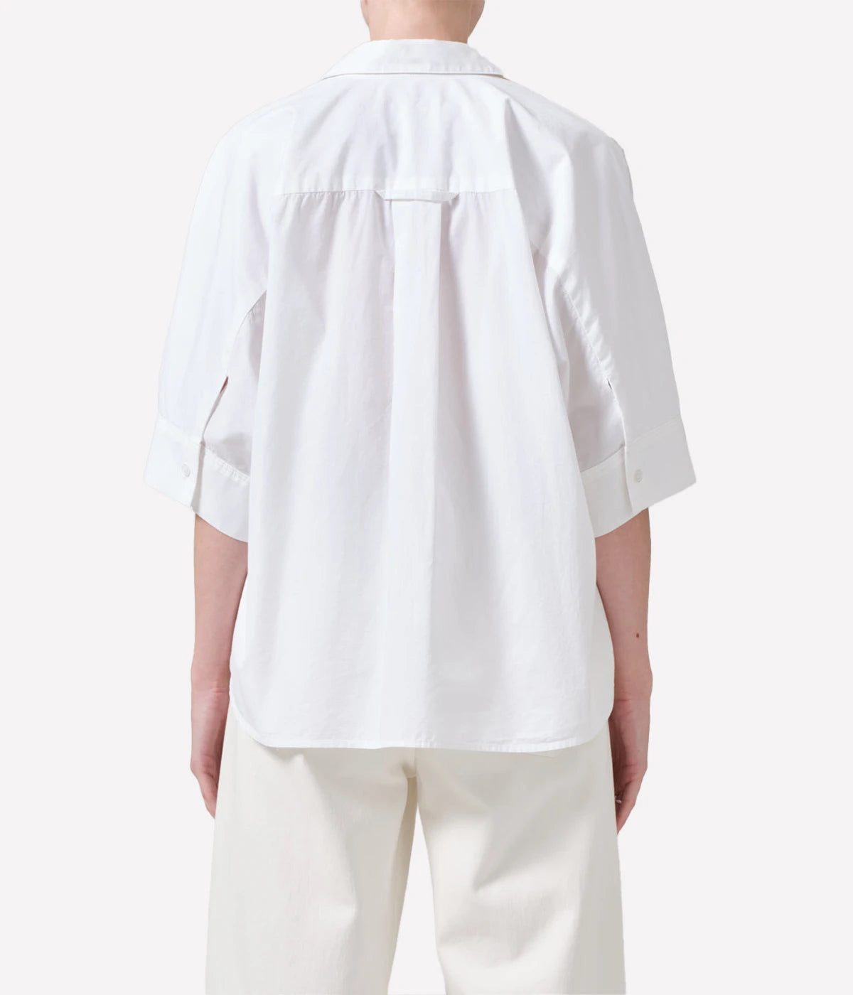 Oversized white cotton button-down shirt styled with relaxed trousers for a chic, casual outfit.
