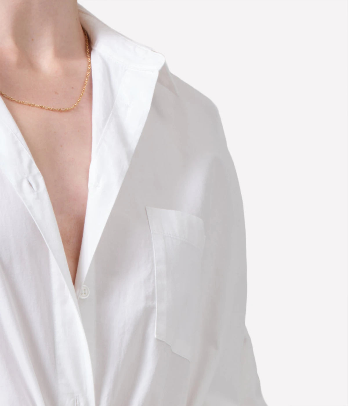 Oversized white cotton button-down shirt styled with relaxed trousers for a chic, casual outfit.