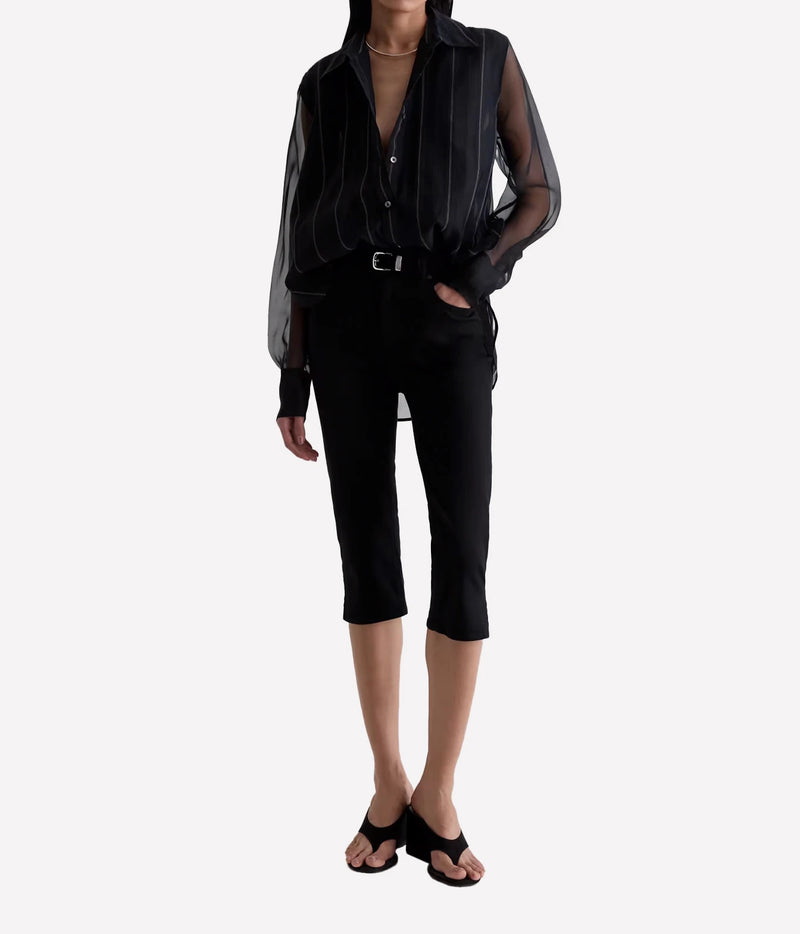 A model wearing a black sheer long-sleeve button-up shirt with vertical pinstripes, paired with black cropped pants and black sandals, against a light gray background.