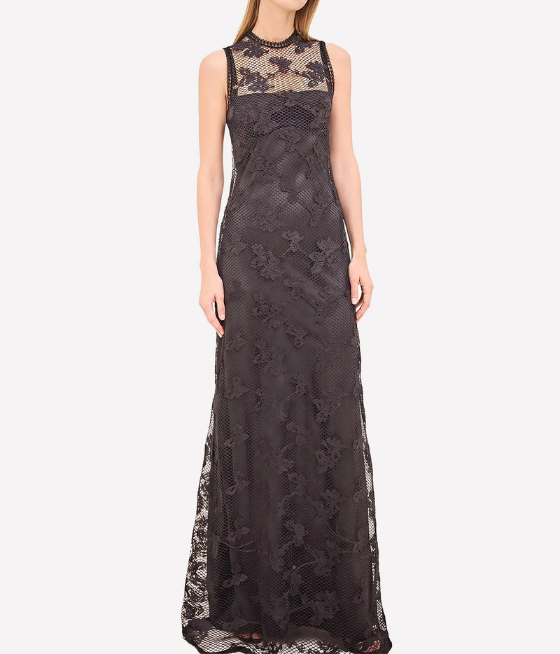 A sleeveless black lace maxi dress with a sheer mesh high neck and floral lace applique, shown on a model against a light gray background.