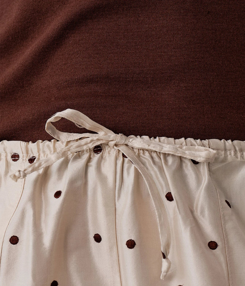 Close-up of a garment with a dark brown ribbed upper section and cream-colored lower section featuring small dark brown polka dots and a matching cream drawstring tie at the waist.