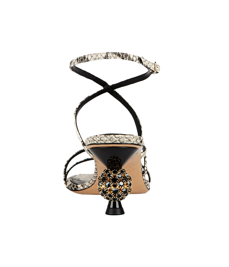 The sandal has black strappy lines wrapping around the foot and ankle, a black heel counter, a beige insole, a snakeskin-patterned strap