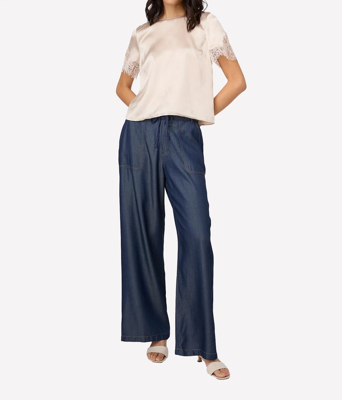 Full-length view of model wearing Cami NYC Marguerite Silk Top in Oat with wide-leg dark denim