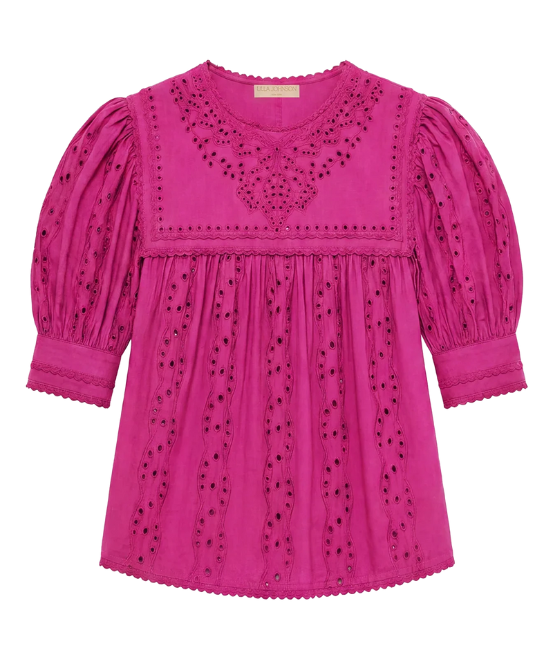 A bright pink eyelet cotton blouse with puffed sleeves, scalloped edges, and embroidered detailing on the chest and bodice, shown flat against a white background.