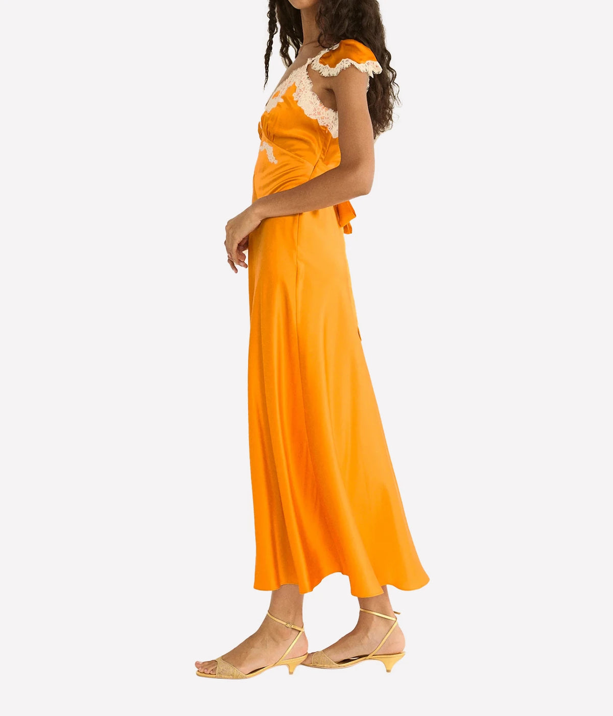 DÔEN Fiona Dress in Tangerine, side model view highlighting the silk satin and cap sleeves.