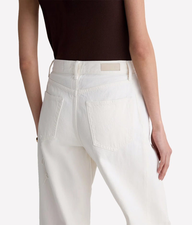 A close-up back view of a model wearing off-white high-waisted jeans with a dark brown top, showing the back pockets and waistband details against a light gray background.