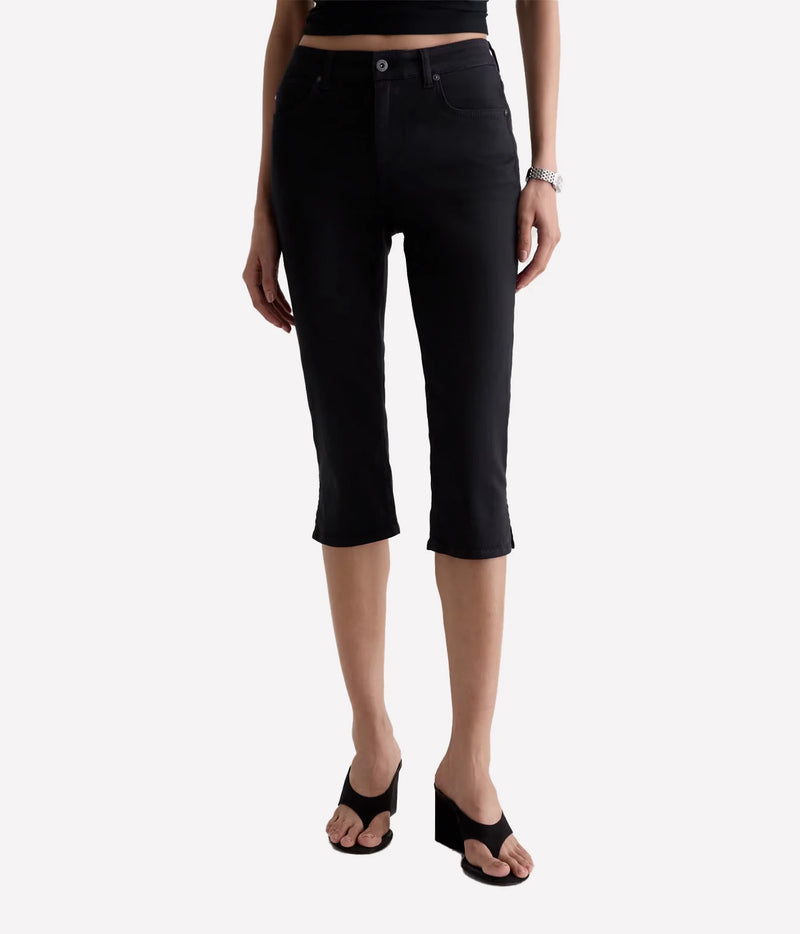 A model wearing black cropped capri jeans, styled with black wedge sandals and a black crop top against a light gray background.
