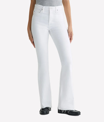 A high-rise white bootcut jean with raw, stringy hems, with a skinny fit through the legs before opening into a subtly flared shape. Wash and wear this flattering AG jean with everything!  