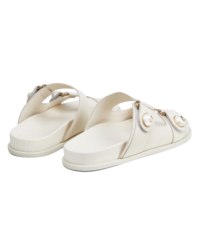 A pair of off-white leather slide sandals with double straps and gold-tone hardware, displayed on a clean white background.