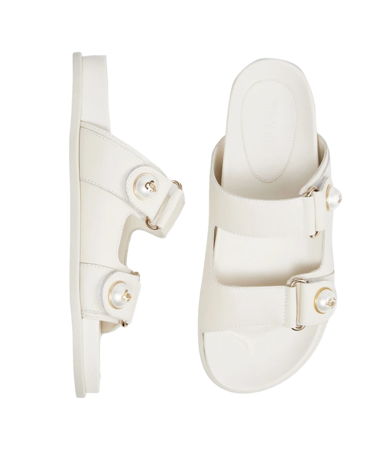 A pair of off-white double-strap slide sandals with gold-tone hardware and pearl embellishments, shown from two angles on a plain white background.