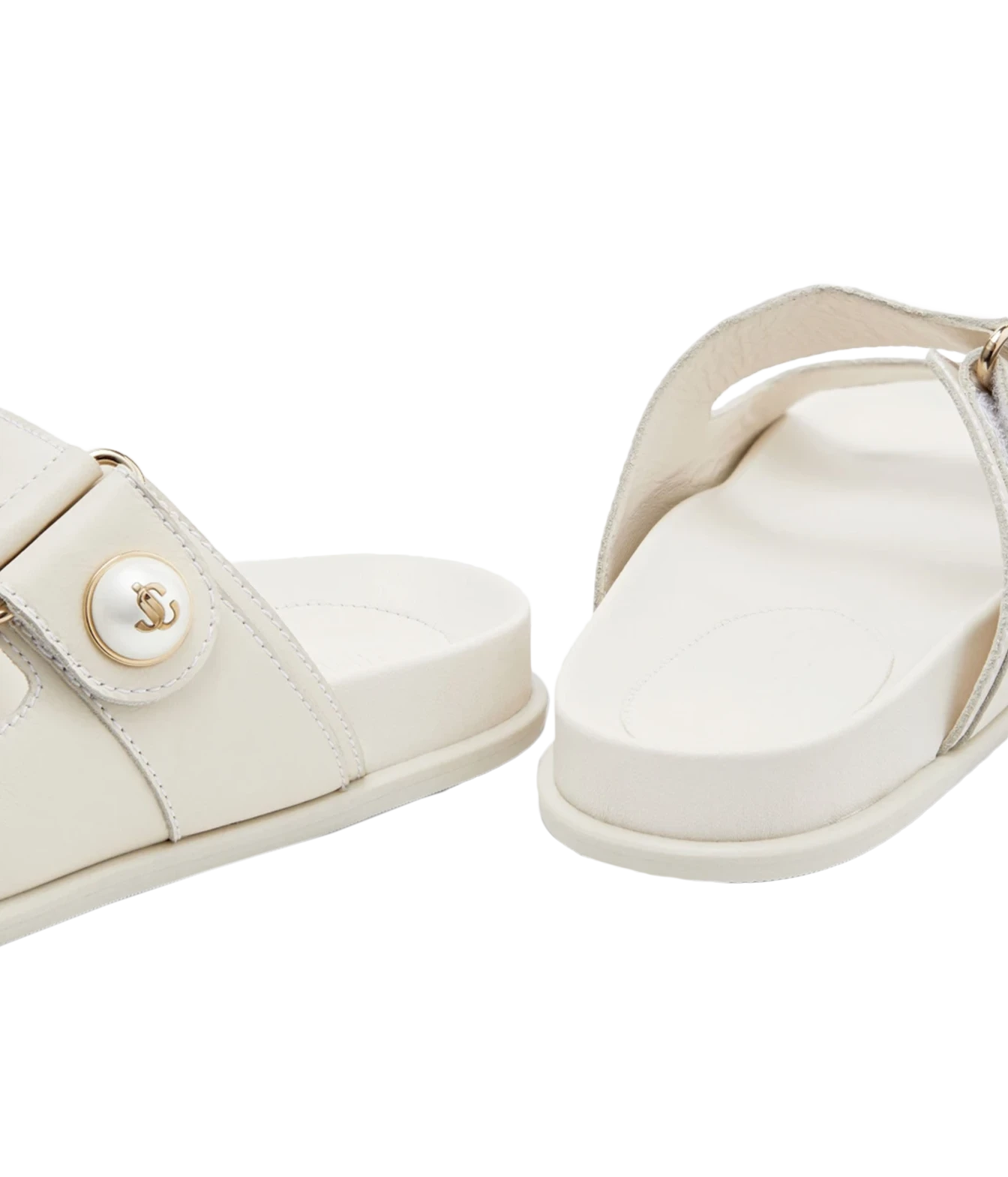A pair of off-white leather slide sandals with a decorative round button featuring an interlocking CC logo, shown on a clean white background.