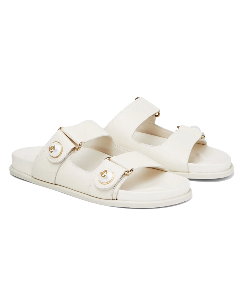 A pair of off-white double-strap slide sandals with gold-tone hardware and decorative round studs, shown on a plain white background.