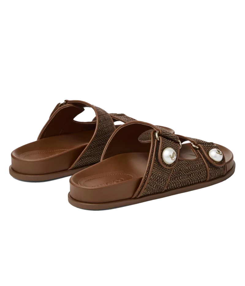 A pair of brown slide sandals with textured woven straps and decorative white pearl-like accents, shown on a plain white background.