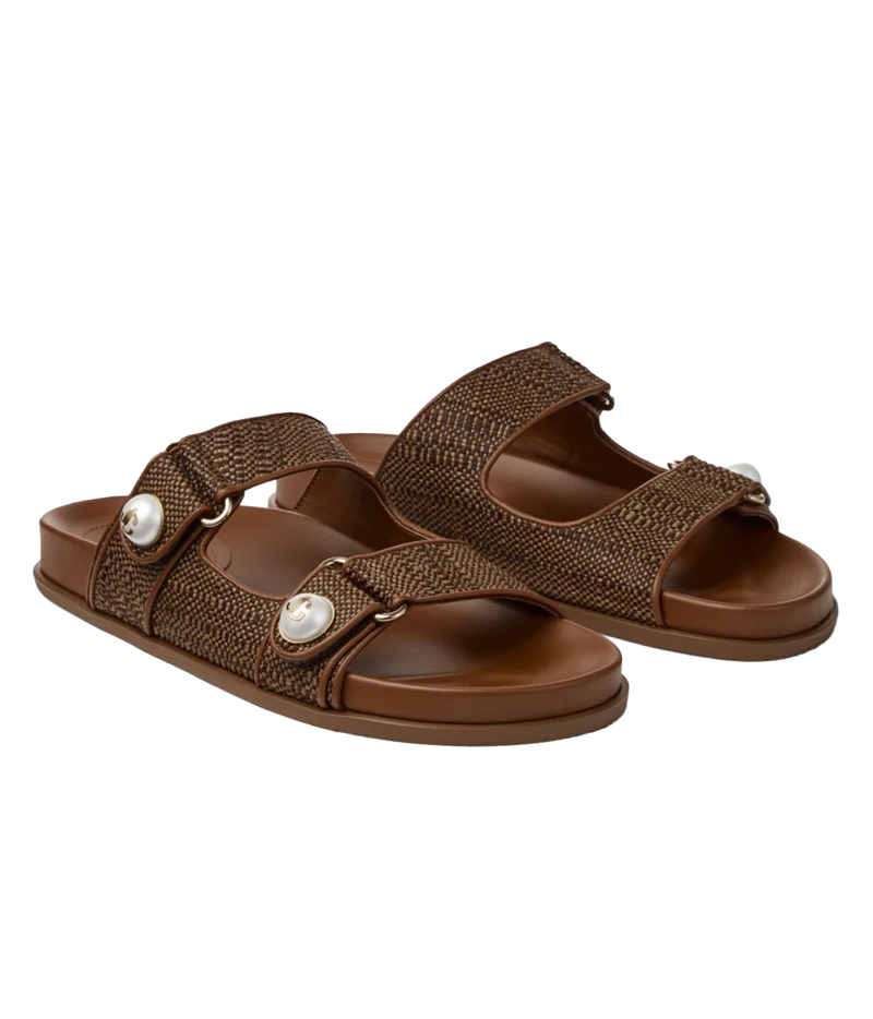 A pair of women's brown slide sandals with woven textured straps, adjustable hook-and-loop closures, and decorative white pearl-like studs, shown on a plain white background.