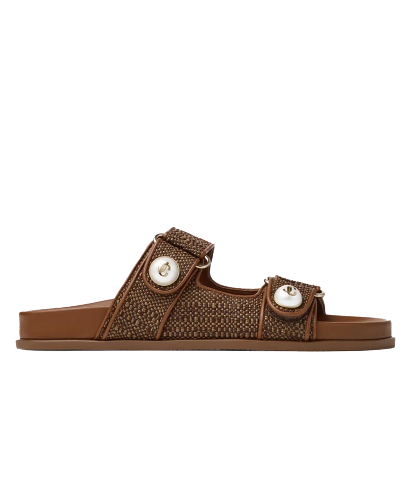 A single brown slide sandal with a woven patterned strap, two adjustable straps with white circular accents, and a flat sole, shown against a plain white background.