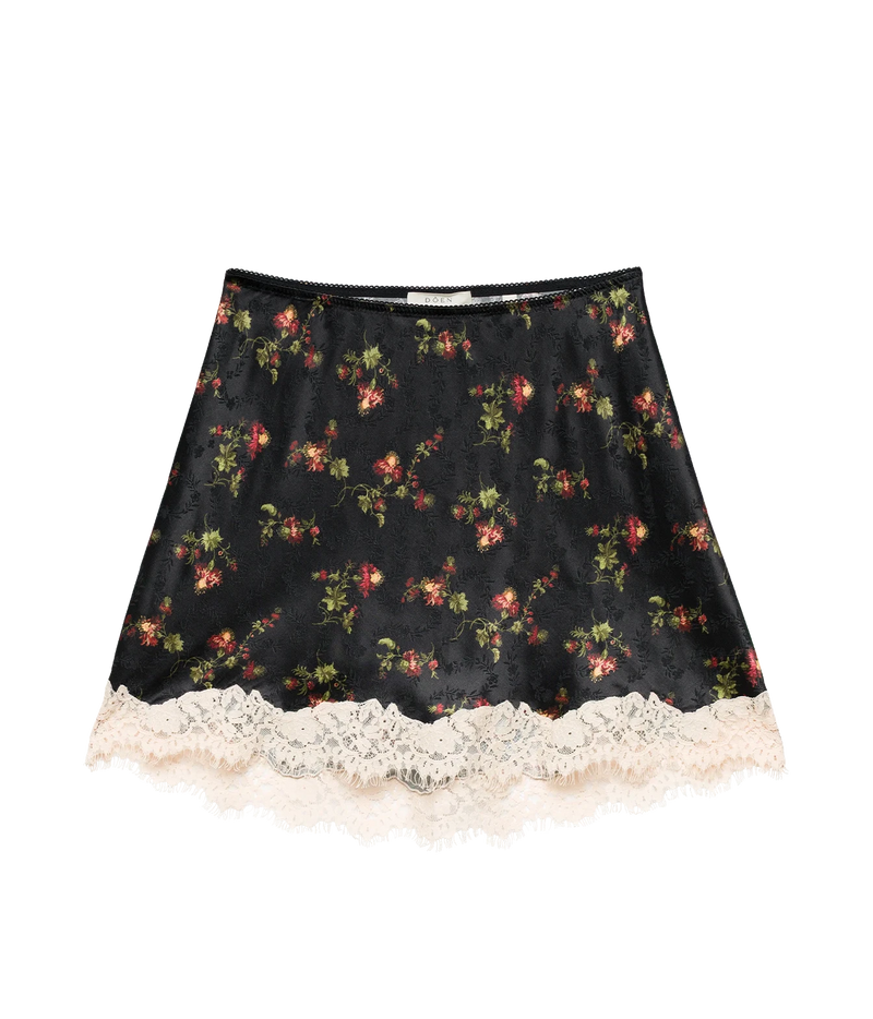 DÔEN Giulietta Skirt In Noir Hillside Thistles laid flat, showing the black floral print with red and pink blooms and the cream scalloped lace hem