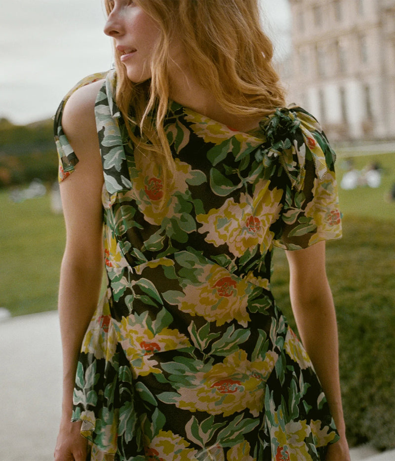 Close-up front view of a model wearing the DÔEN Hesperia Dress In Hanbury Garden, showing the floral print, gathered shoulder tie and short sleeves