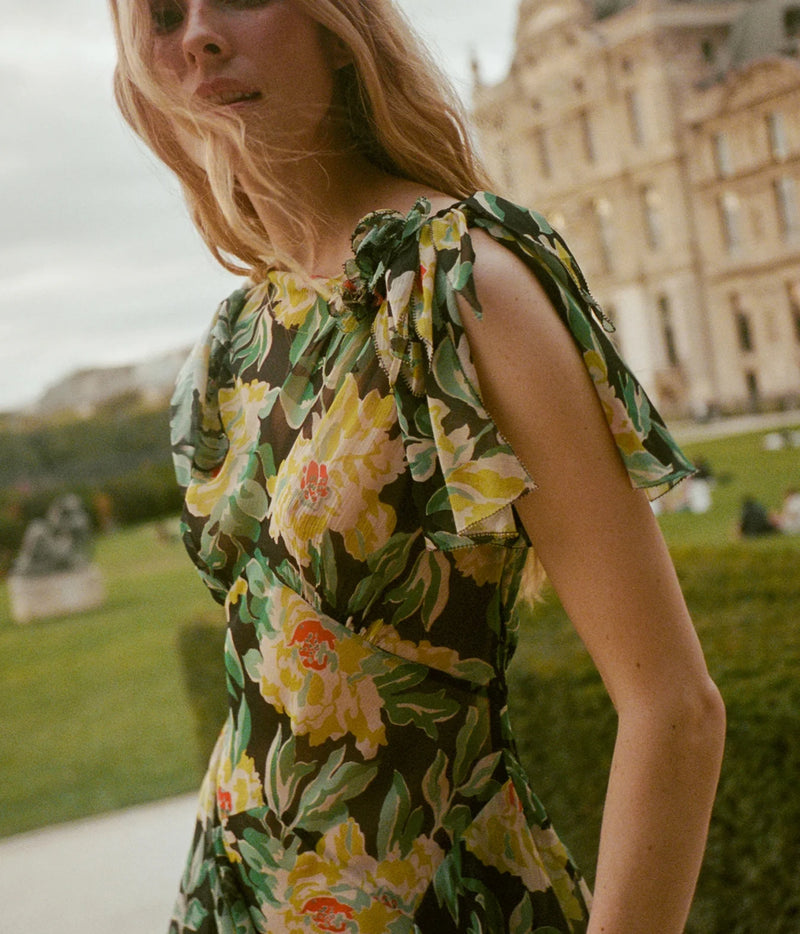 Detail of a model wearing the DÔEN Hesperia Dress In Hanbury Garden, showing the ruffled tie shoulder and the large floral print on the bodice