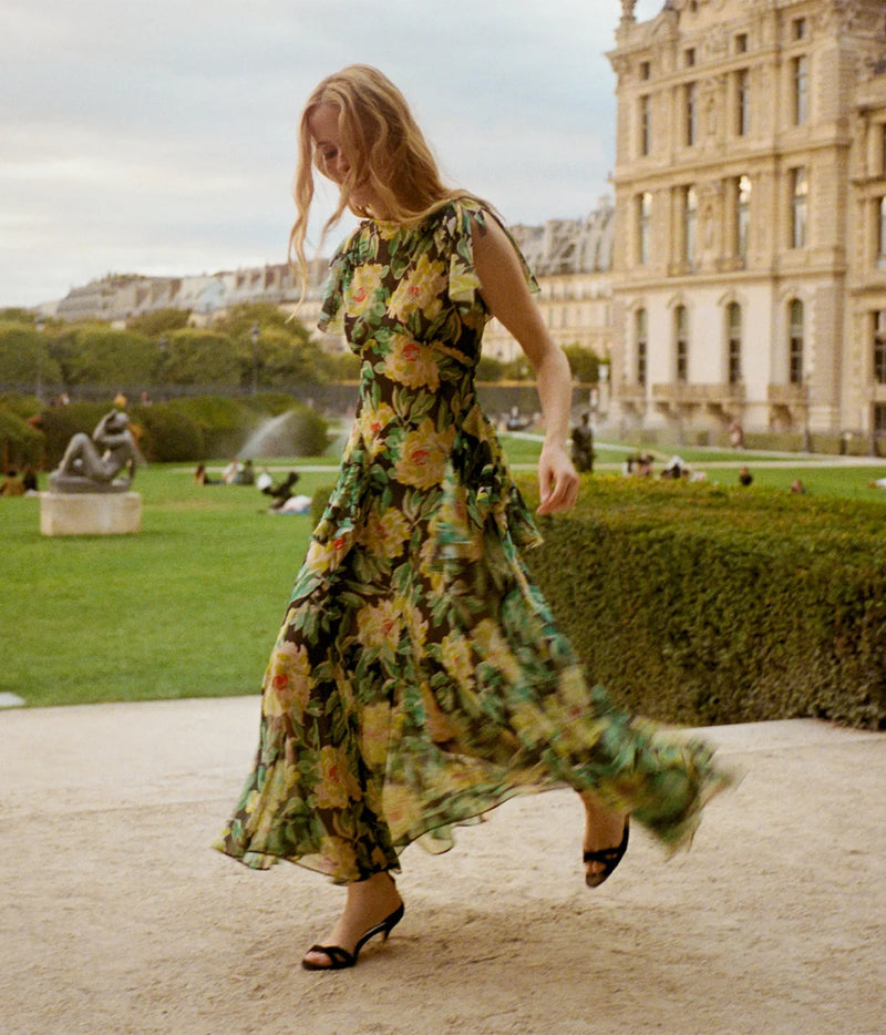 Model walking in the DÔEN Hesperia Dress In Hanbury Garden with black heeled sandals, showing the flowing hem of the maxi skirt