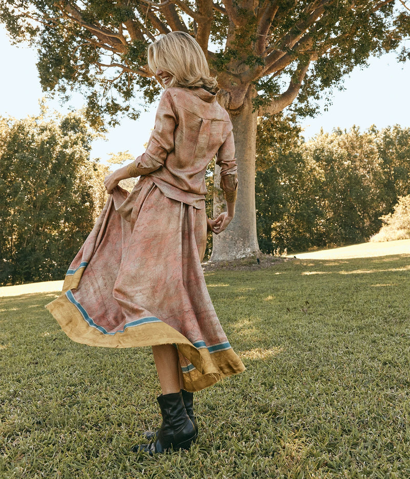 Pierre-Louis Mascia Aloe Silk Skirt in Terracotta Multi, back view on model with the matching Aloe Shirt and black lace-up boots, twirling the skirt under a large tree