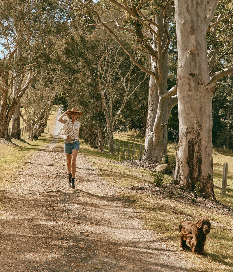 DÔEN Millie Top In Narcissus Bloom, worn on model with denim shorts, walking along a country track with a spaniel