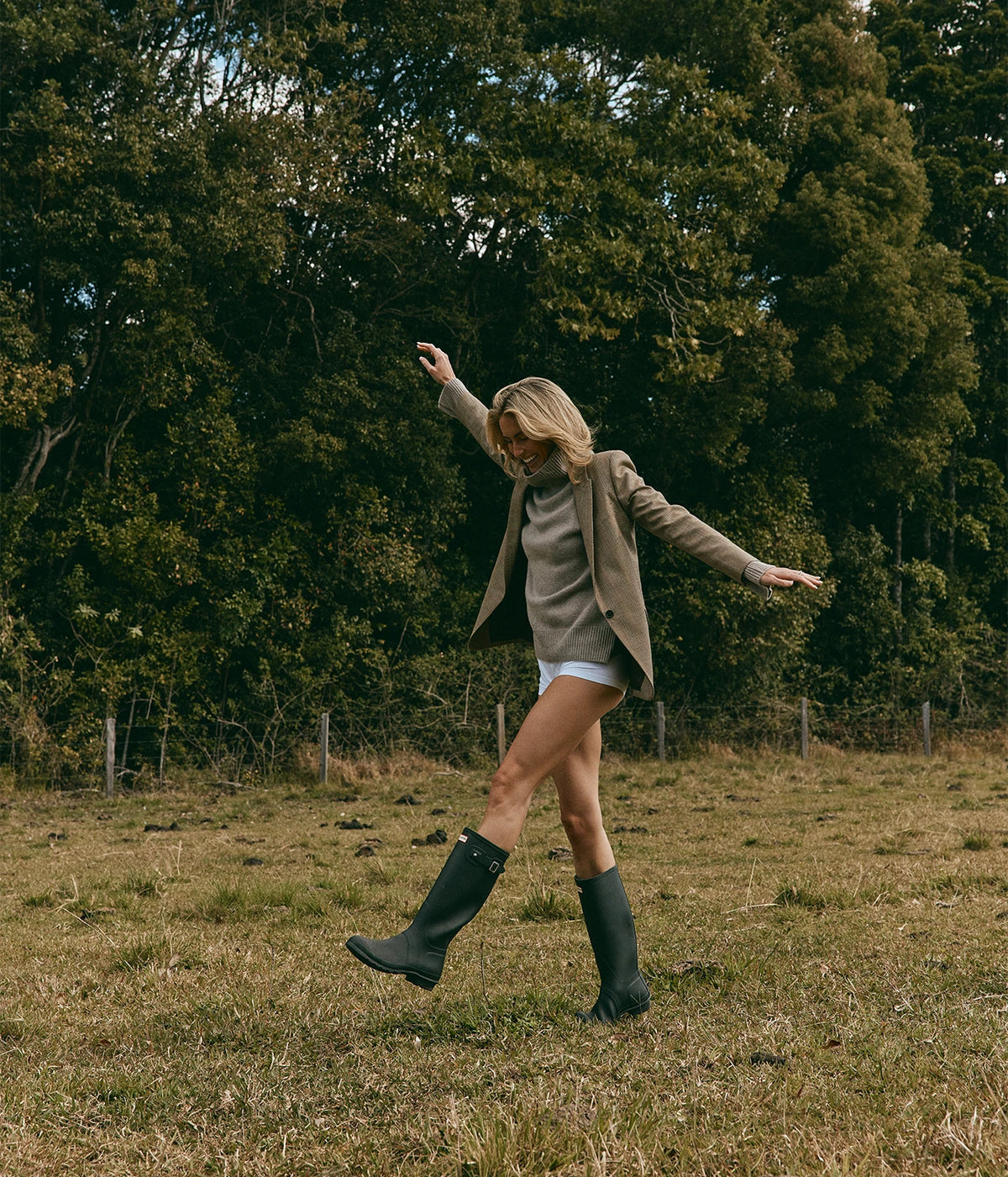 Nili Lotan Diane Blazer In Glen Plaid, worn on model over a taupe turtleneck with green rubber boots, mid-step in a paddock
