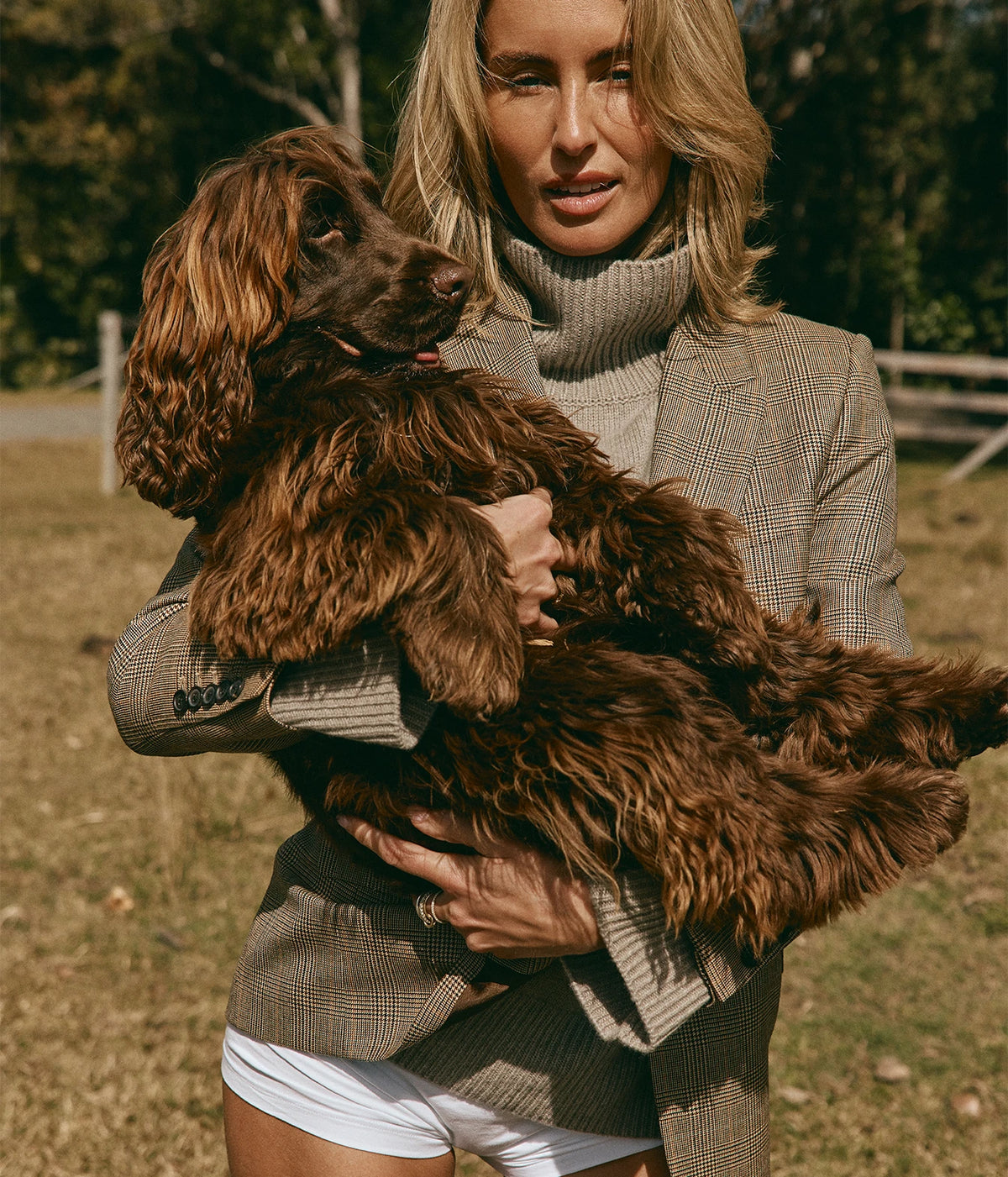 Nili Lotan Diane Blazer In Glen Plaid, close-up on model over a taupe turtleneck, cuddling a brown spaniel