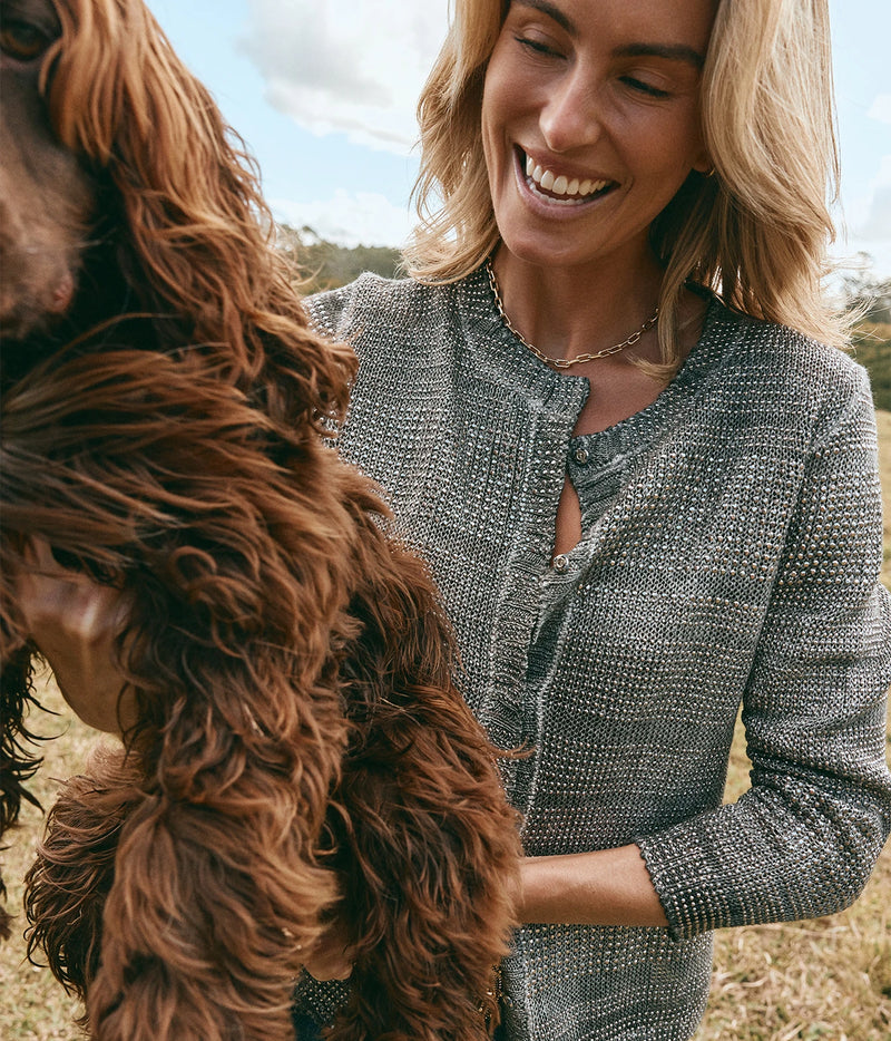 Avant Toi 15Th Anniversary Studded Cardigan In Huskey, close-up on model in the grey studded cardigan, smiling beside a brown spaniel