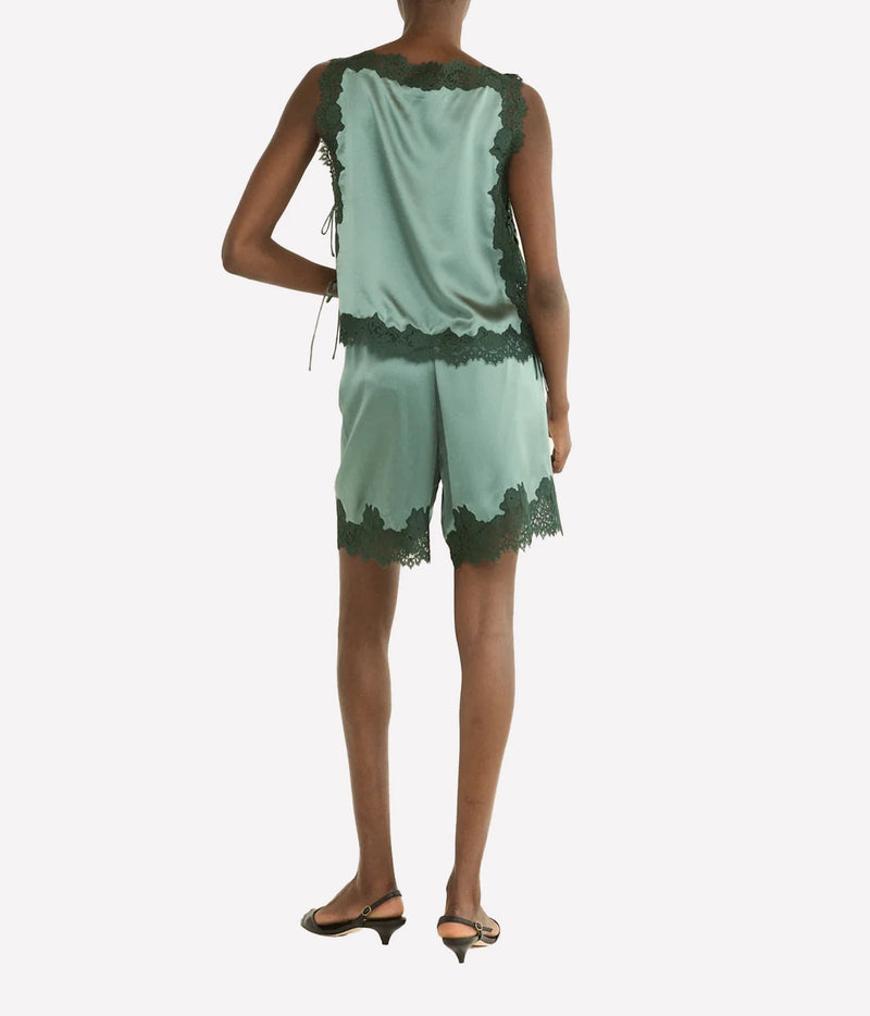A model shown from the back wearing a green satin top and shorts with dark green lace trim, consisting of a sleeveless top and matching shorts, paired with black slingback heels.