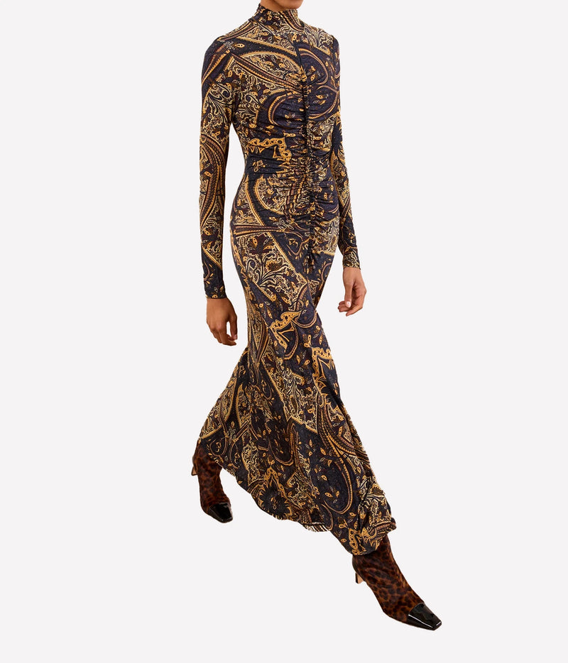 A long-sleeve high-neck maxi dress with a dark navy and gold paisley pattern, modeled on a plain light gray background.