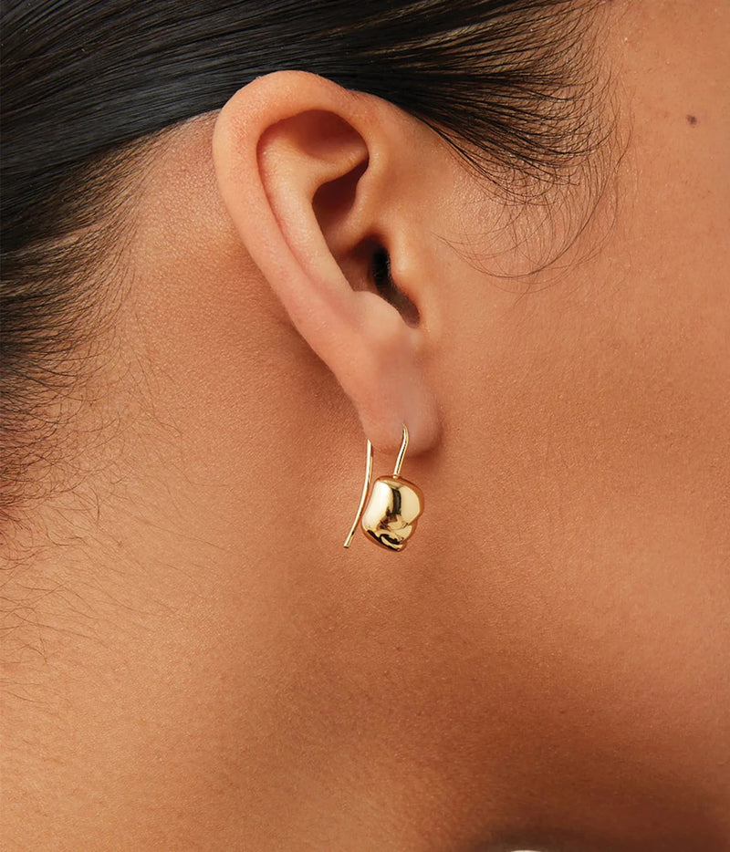 Side profile close-up of a model's ear wearing the Jenny Bird Rue Drop Earrings in Gold with her hair tied back