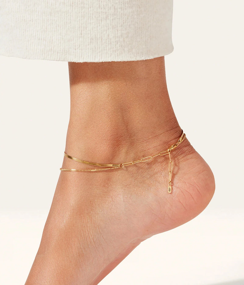 Close-up of the Jenny Bird Surfside Anklet in Gold worn on a bare ankle with cream trousers, showing the layered strands from the front